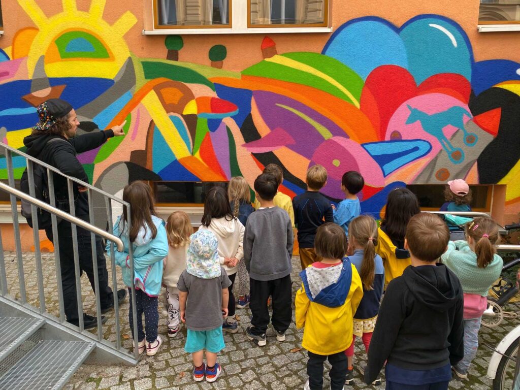 Fassade der Kita Kleine Auguststraße der Kindergärten City mit buntem Graffiti wird von Kindern bestaunt